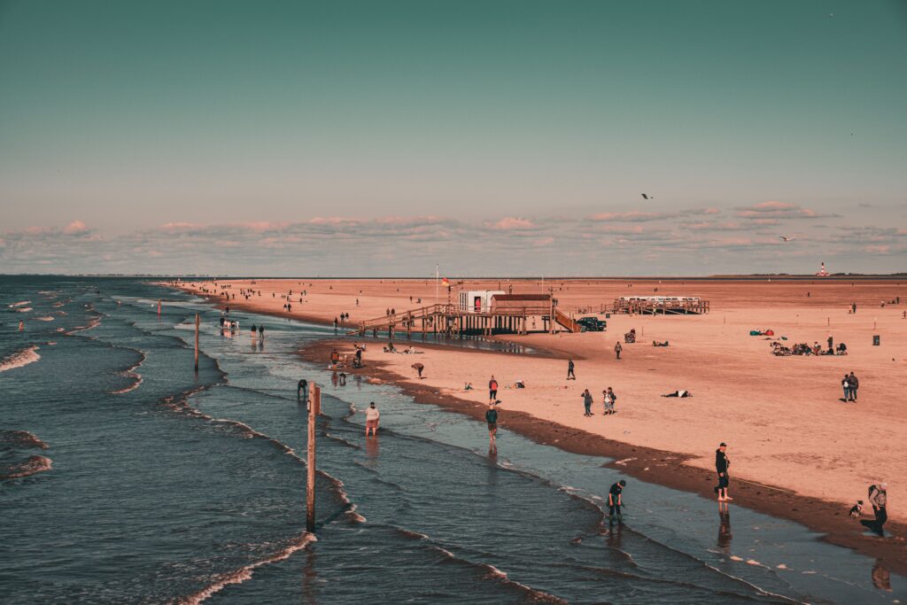 A serene beach view with people enjoying the sun and sand under a clear blue sky.